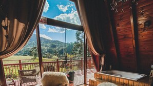 A cozy room with large windows, wooden flooring, and a view of a lush landscape. - Estância Nazari (Urubici)