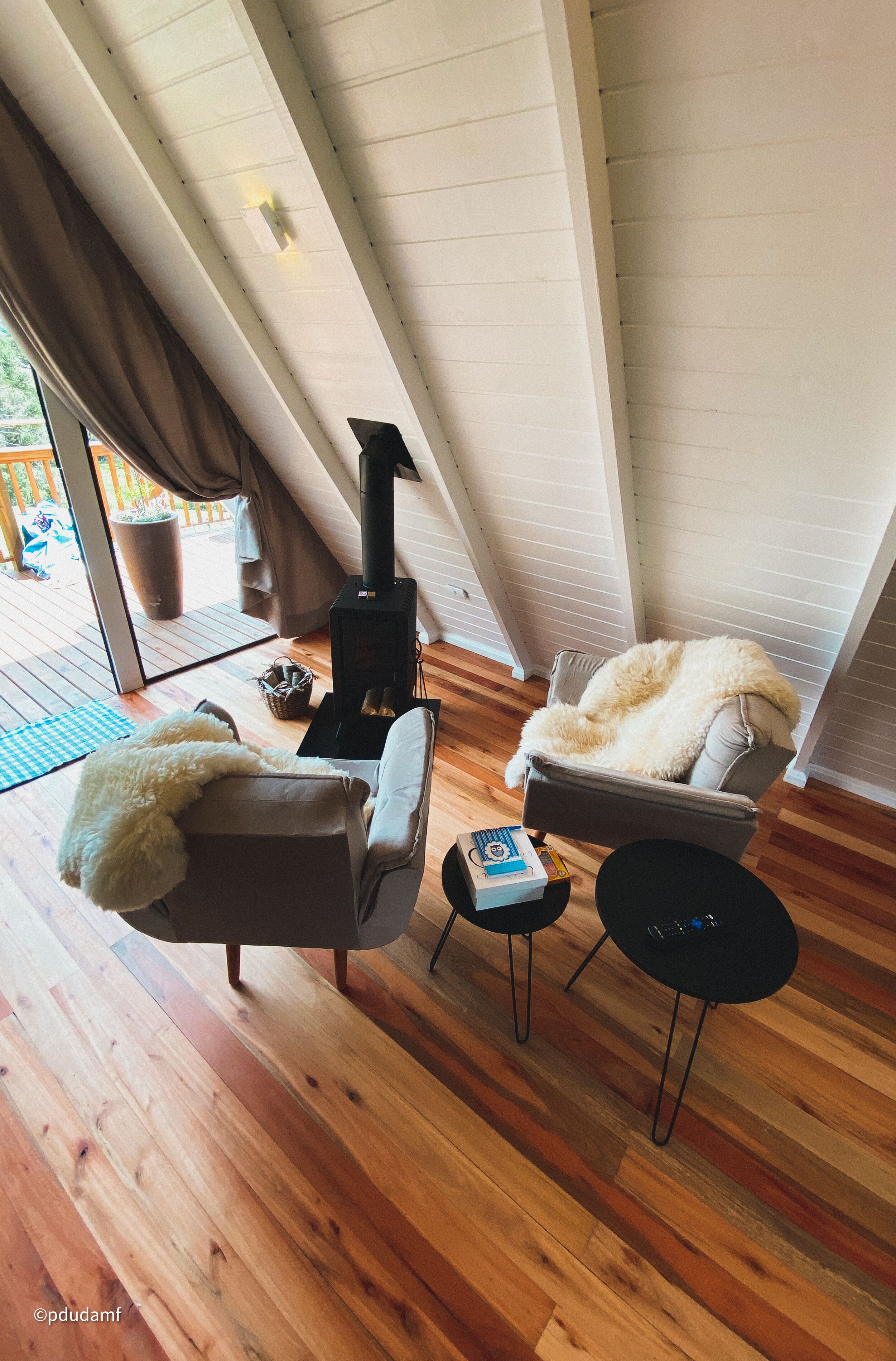 Una habitación acogedora con chimenea, dos sillones, una mesita y vistas al exterior.