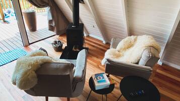 Een gezellige kamer met een open haard, twee stoelen, een tafeltje en uitzicht op de omgeving.