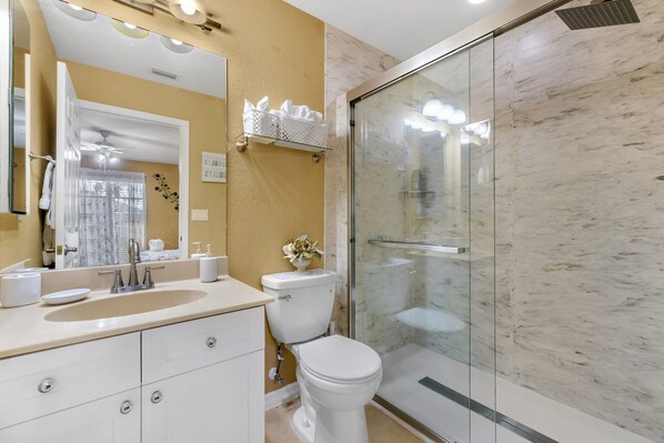 Une salle de bain moderne avec une douche à parois de verre, un lavabo blanc et des toilettes.