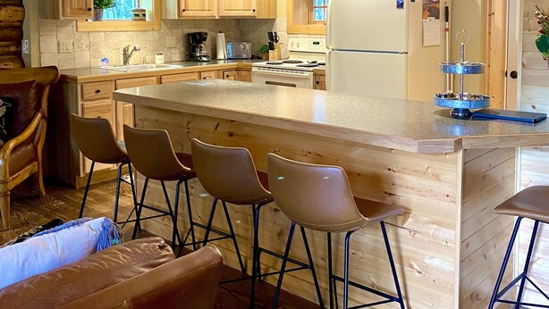 Een moderne keuken met houten kastjes, een groot eiland met barstoelen en een koelkast.
