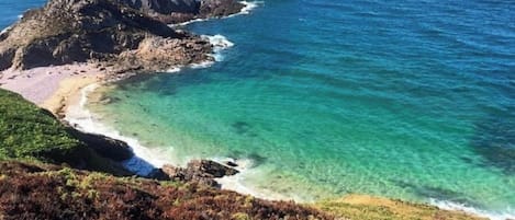 A coastal landscape with rocky outcrops and clear turquoise waters.