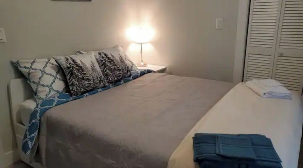 A bedroom with a bed, a bedside lamp, a nightstand, and a closet.