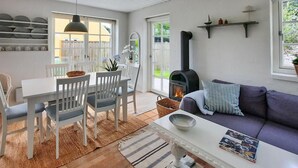 A cozy living room with a fireplace, white furniture, and a view of the outdoors.