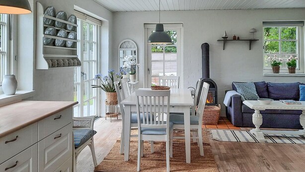 A cozy living room with a fireplace, a dining area with white chairs, and a blue sofa.
