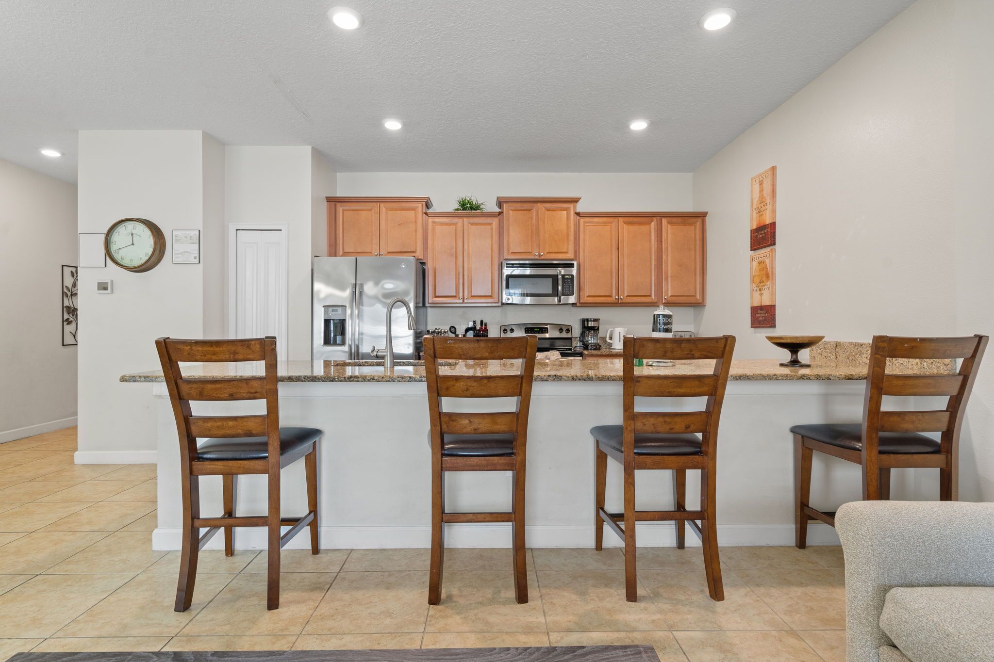 A modern kitchen with wooden cabinets, stainless steel appliances, and a central island with bar stools.