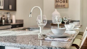 A kitchen counter with a white bowl, a wine glass, and a knife on a placemat.