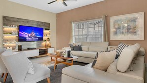 A modern living room with a flat-screen TV, a ceiling fan, a sofa, and a coffee table.
