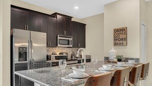 A modern kitchen with dark cabinets, stainless steel appliances, and a granite countertop.