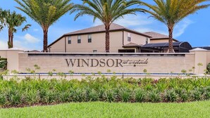 Een gebouw met een bord waarop 'WINDSOR at Westside' staat, omringd door palmbomen en groen.
