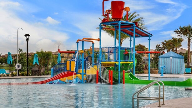Een waterpark met een centraal speelconstructie, glijbanen en een zwembad.
