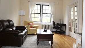 Una sala de estar con un sofá de cuero, un sillón amarillo, una mesa de centro de madera y una lámpara.