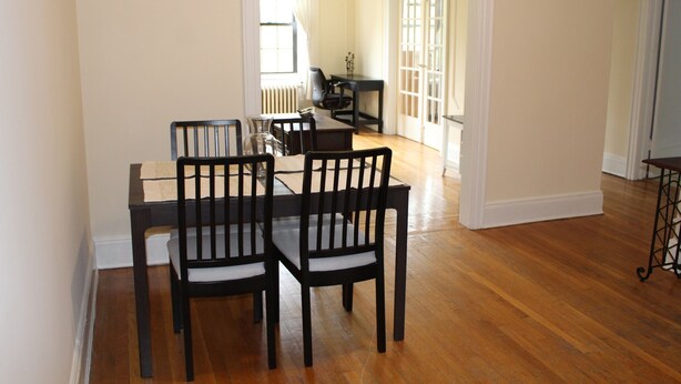 Un comedor con una mesa y sillas de madera, un radiador y una puerta que da a otra habitación.