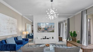 Ein modernes Wohnzimmer mit einem blauen Sofa, einem grauen Couchen und einer weißen Unterhaltungsanlage mit Fernseher.