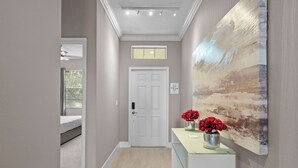 Ein Flur mit einer weißen Tür, einem kleinen Fenster und einem Gemälde an der Wand.