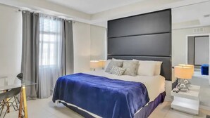 Quarto de hotel moderno com uma cama grande, uma escrivaninha e uma cadeira.