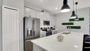 Een moderne keuken met witte kasten, roestvrijstalen apparatuur en een centraal eiland.
