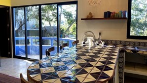A modern kitchen with a large island, a dining area, and a view of a pool through glass doors. - Digital Nomad's Dream in Paradise I (Sayulita)