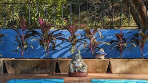 A meditation area with a statue, potted plants, and blue mats on a tiled floor. - Digital Nomad's Dream in Paradise II (Sayulita)