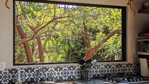 A kitchen with a large window overlooking a lush garden. - Digital Nomad's Dream in Paradise II (Sayulita)