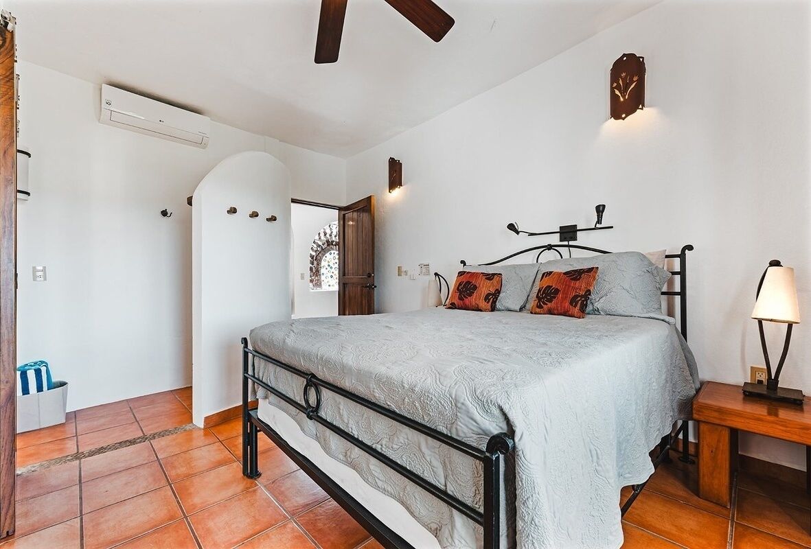 Een slaapkamer met een bed, nachtkastje, lamp en een wandklok.