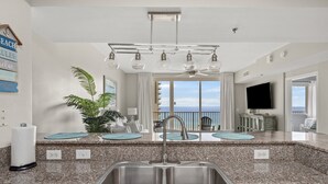 A modern kitchen with granite countertops, a double sink, and a ceiling fan. - Shores of Panama 814~ 2 Bdrm (Panama City Beach)