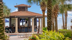 A poolside bar area with outdoor seating, palm trees, and a clear view of the ocean. - Shores of Panama 814~ 2 Bdrm (Panama City Beach)