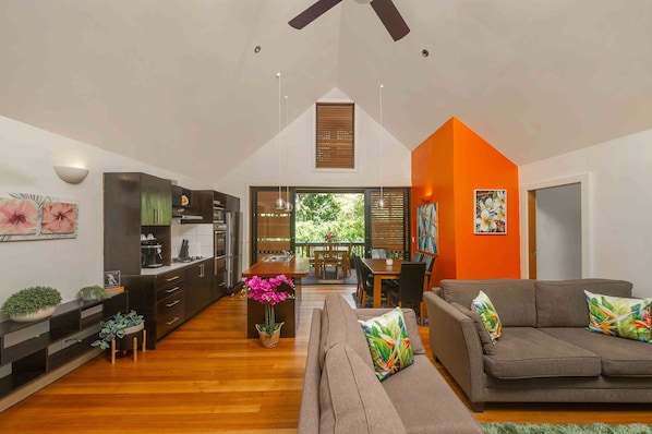 A modern kitchen with dark cabinets, a wooden dining table, and a sofa with colorful cushions. - Cook Islands Holiday Villas Turtle (Rarotonga)