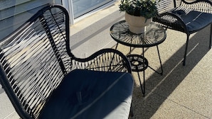 Un espace patio aménagé avec deux chaises en osier noir et une petite table ronde sur laquelle est posée une plante en pot.
