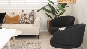 Un salon moderne comprenant un canapé, deux fauteuils, une table à manger et une grande plante.
