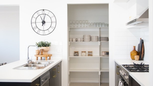 Une cuisine moderne dotée d’un îlot central, d’étagères intégrées et d’une horloge murale.
