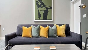 A modern living room with a dark sofa, yellow and green cushions, and a framed poster on the wall. - Petaluma Warehouse Loft Collection (Petaluma)