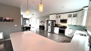 A modern kitchen with white cabinets, stainless steel appliances, and pendant lighting. - Country Living and Views; Full RV hookup available (Moscow)