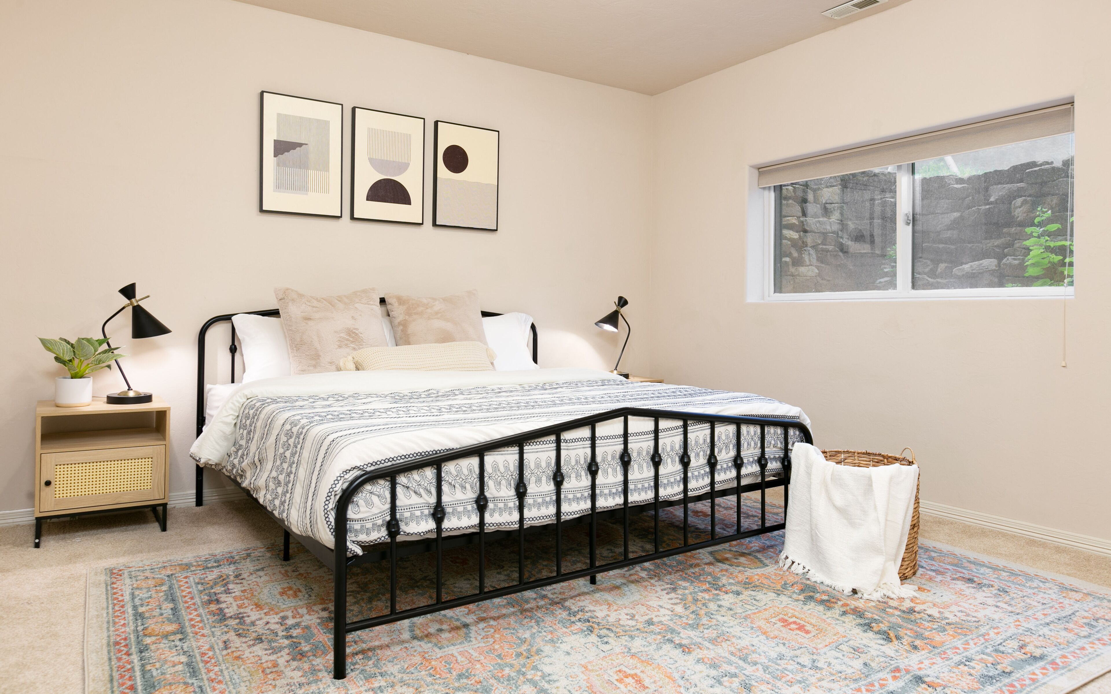 Une chambre à coucher avec un lit, des tables de chevet, une fenêtre et un tapis à motifs.