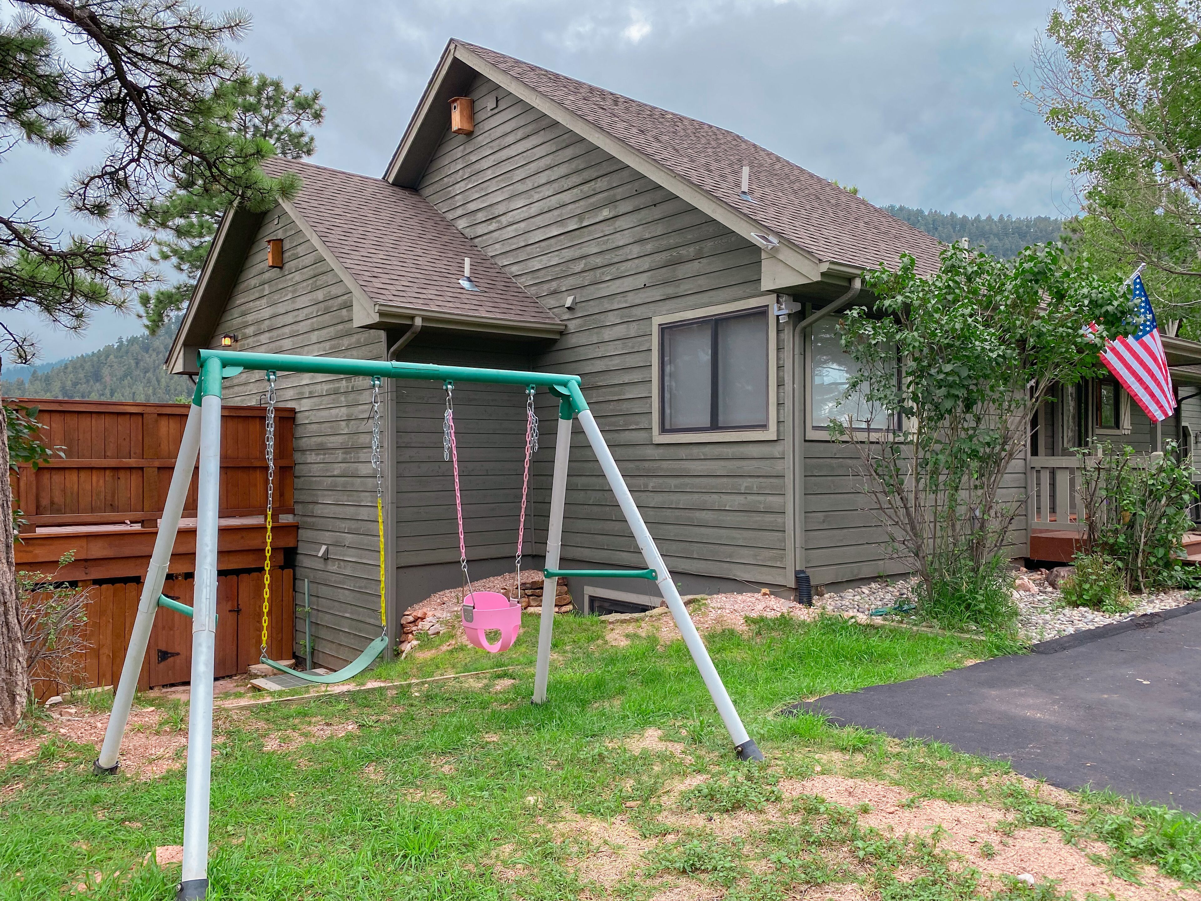 Ein Haus mit Schaukel und Garten, einem Holzzaun und einer amerikanischen Flagge.