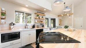 Une cuisine moderne avec des meubles blancs, un grand îlot central et des luminaires suspendus.