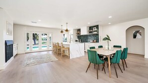 A spacious living area with a dining table, chairs, and a kitchen in the background. - 3BR w/ Heated Pool! Mins from ASU and Golf! (Tempe)