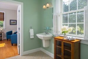 Une salle de bain avec un lavabo, un miroir et une fenêtre.
