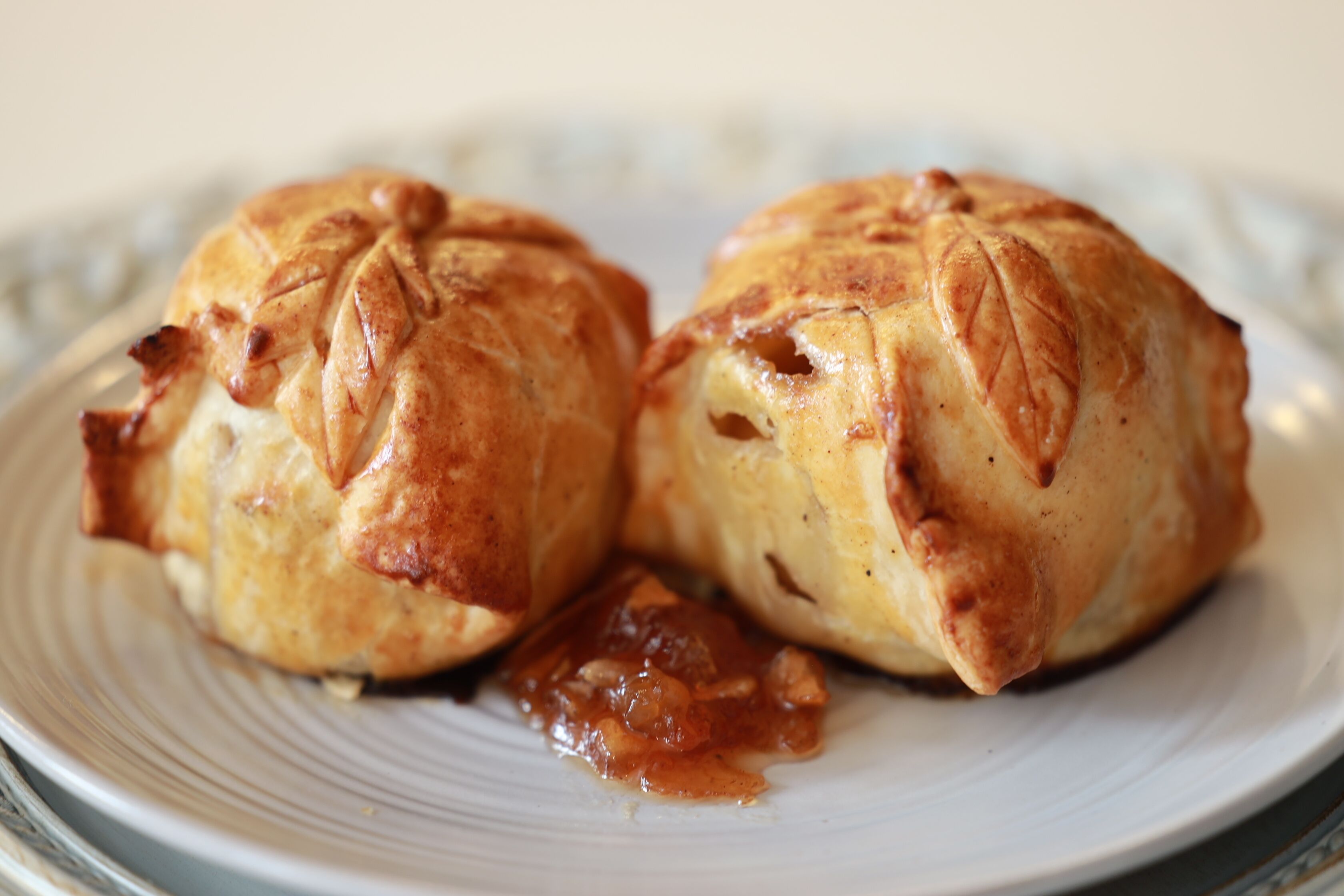 Deux pâtisseries sur une assiette, accompagnées d’une sauce.