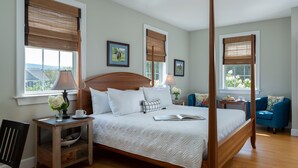 Une chambre spacieuse avec un grand lit, une tête de lit en bois et deux tables de chevet avec des lampes.