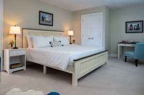 Une chambre à coucher avec un lit, des tables de chevet, un bureau et des chaises.