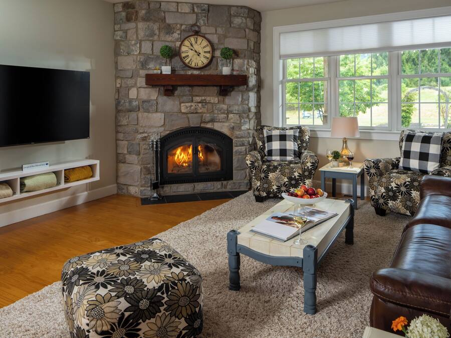 Una sala de estar con chimenea de piedra, televisor y un conjunto de sofás.