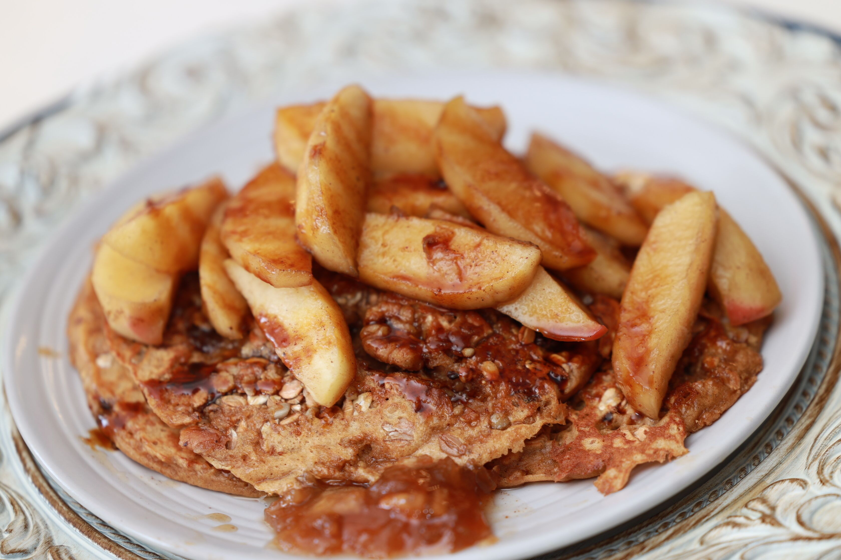A plate of oatmeal topped with apple slices and pecans.