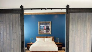 Una camera da letto con un letto, due comodini e un cartello appeso al muro.