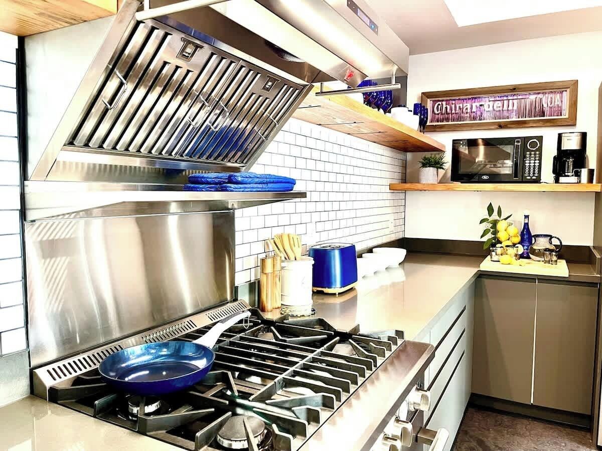 Een moderne keuken met een roestvrijstalen fornuis, een magnetron en een koffiezetapparaat op het aanrecht.