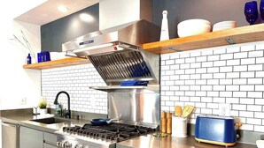 Una cucina moderna con un piano cottura, forno e un tostapane in acciaio inossidabile, tutto in blu.