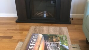 A book titled "Oregon Coast" on a wooden coffee table in front of a fireplace.