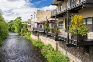 A riverside building with balconies, a stone facade, and a bridge over the water. - Charming Parkside Bungalow-2 blocks from downtown! (Silverton)