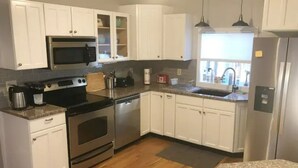 A kitchen with white cabinets, stainless steel appliances, a microwave, oven, and a refrigerator.