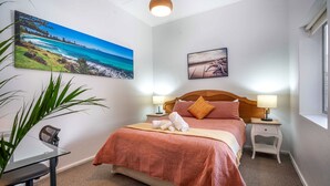 A hotel room with a bed, two bedside tables, a desk, and a large window.